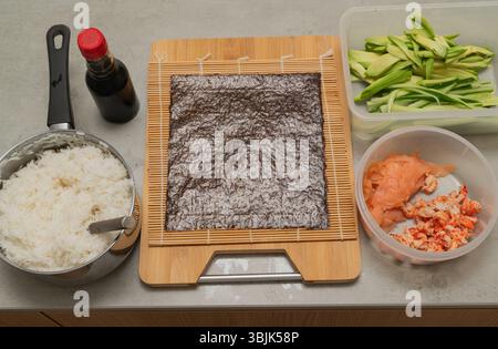 Gli ingredienti per il sushi e gli utensili essenziali sono ben disposti sul bancone della cucina Foto Stock