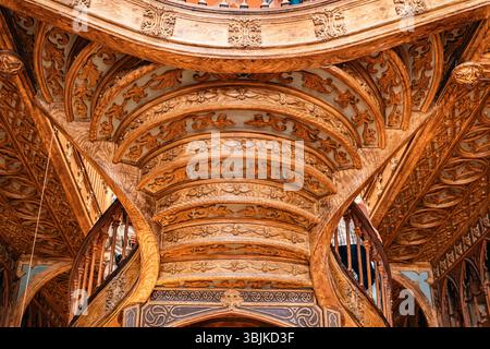 Magnifica scala in legno intagliato con intricati dettagli all'interno della famosa libreria Livraria Lello, che mostra l'architettura storica. Porto, Portogallo - 11 giugno 2025 Foto Stock