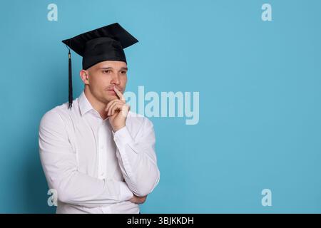 Studente premuroso dopo la laurea su sfondo azzurro. Spazio per il testo Foto Stock
