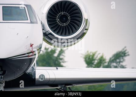 Primo piano del jet privato Gulfstream che mostra la finestra della cabina di pilotaggio, la navicella del motore e i dettagli dell'ala lucida. Pale del turboventilatore chiaramente visibili contro sfocature Foto Stock