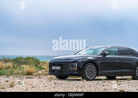 Balykchy, Kirghizistan - 12 maggio 2024: Vista frontale di una grandiosità Hyundai nera 2023 (GN7) parcheggiata su una strada sterrata che si affaccia su un lago blu Foto Stock