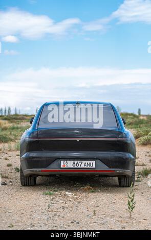 Balykchy, Kirghizistan - 12 maggio 2024: Vista posteriore di una grandiosità Hyundai nera 2023 (GN7) parcheggiata su un sentiero sterrato sotto un cielo blu con alcune nuvole Foto Stock