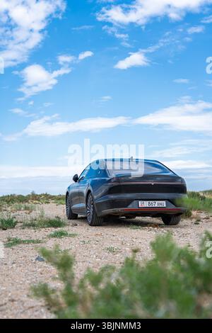 Balykchy, Kirghizistan - 12 maggio 2024: Vista posteriore di una Hyundai Grandeur nera 2023 (GN7) parcheggiata su un sentiero sterrato con un cielo blu e una vegetazione sparsa Foto Stock