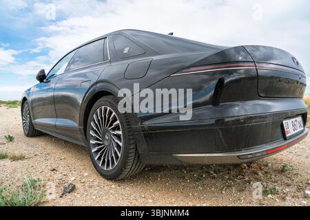 Balykchy, Kirghizistan - 12 maggio 2024: Vista posteriore di una Hyundai Grandeur nera 2023 (GN7) parcheggiata su un sentiero sterrato con riflessi sul corpo Foto Stock