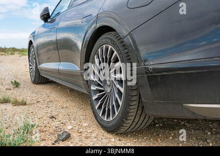 Balykchy, Kirghizistan - 12 maggio 2024: Primo piano della ruota posteriore e del corpo laterale di una Hyundai grandeur nera 2023 (GN7) su un sentiero sterrato Foto Stock