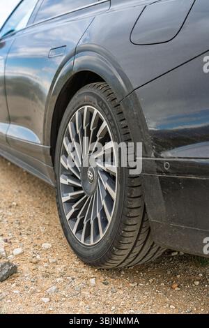 Balykchy, Kirghizistan - 12 maggio 2024: Primo piano della ruota posteriore e del corpo laterale di una Hyundai grandeur nera 2023 (GN7) su un sentiero sterrato Foto Stock