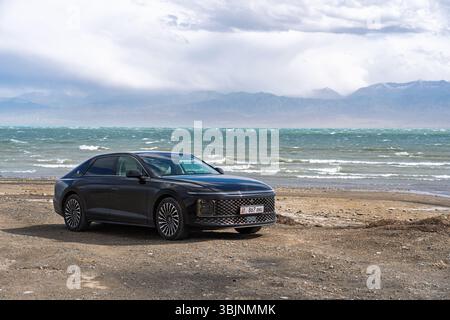 Balykchy, Kirghizistan - 12 maggio 2024: Vista frontale di una grandiosità nera Hyundai 2023 (GN7) parcheggiata su una strada sterrata accanto a un lago ondulato con montagne Foto Stock