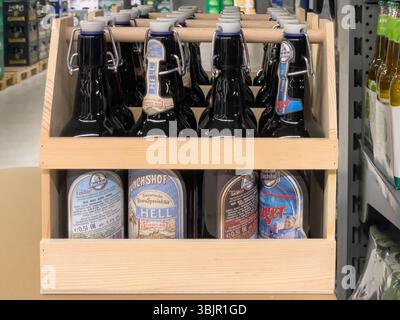 Germania Berlino 7 giugno 2025. Portabicchieri in legno con grandi bottiglie con coperchio basculante di varie birre Monchshof in un negozio di bevande. Confezione rustica per alta qualità Foto Stock