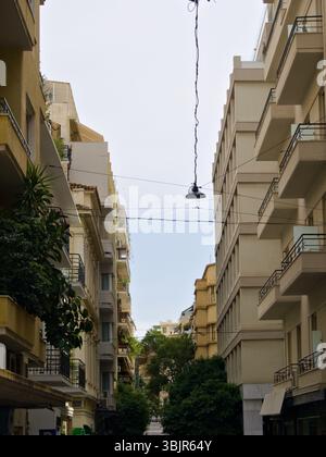 Una tranquilla strada in salita ad Atene, Grecia, fiancheggiata da edifici e alberi gialli e bianchi, catturata dalla calda luce del tardo pomeriggio. Foto Stock