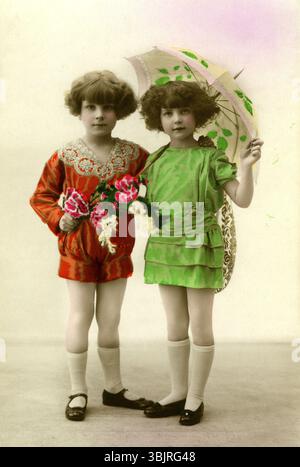 Due ragazze con ombrelli, anni '1930, gemelle con abiti colorati e ombrelli si posano in uno studio, foto storica Foto Stock