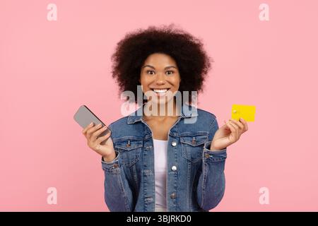 Mobile banking. Felice bella African American Woman Holding smartphone e carta di credito Foto Stock