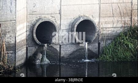 Grondaia. Deflusso d'acqua da una via di scarico (smaltimento dell'acqua, drenaggio delle tempeste), due tubi e acqua a flusso lento (deflusso diretto) dopo la pioggia Foto Stock