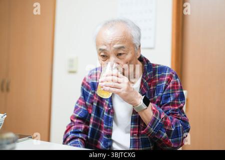 Un uomo giapponese alla fine degli anni '70, che indossa pigiami a scacchi, si diverte a giocare da solo in una stanza d'appartamento soffusa in Giappone. La calda atmosfera lo suggerisce Foto Stock