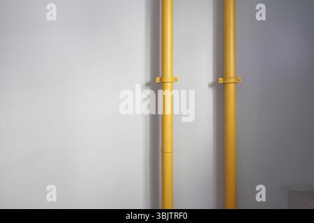 Due tubi gialli montati su una parete grigia in un ambiente moderno Foto Stock