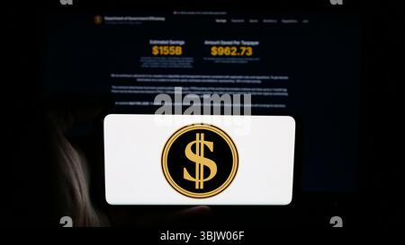 Stoccarda, Germania - 04-17-2025: Persona che detiene un cellulare con il logo del Dipartimento dell'efficienza del governo degli Stati Uniti (DOGE) sullo schermo davanti alla pagina web. Foto Stock