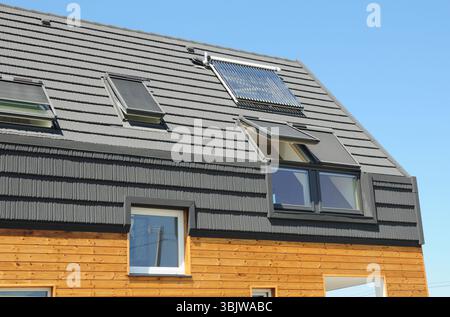 Moderno tetto passivo con lucernario, scaldabagno solare, pannelli solari, tegole di asfalto. Foto Stock
