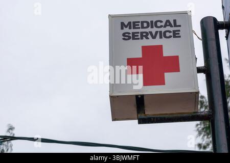 Gili, Lombok, Indonesia - 3 gennaio 2025: L'insegna per il servizio medico è appesa su un edificio. Il cartello è bianco e arancione con una croce rossa. Il cielo è BL Foto Stock