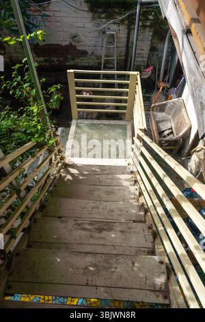 Scala con ringhiera e sedia in cima. Le scale sono in legno e la ringhiera è in metallo Foto Stock