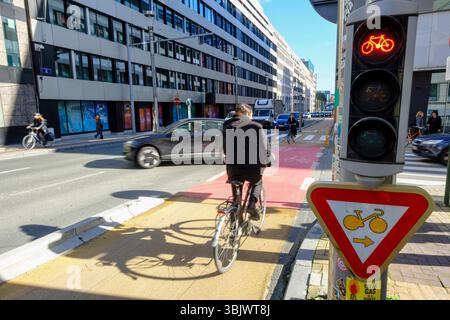 Belgio, Bruxelles: Infrastrutture ciclabili in città per un trasporto sostenibile, piste ciclabili. Ciclisti su una pista ciclabile all'angolo della strada "rue Foto Stock