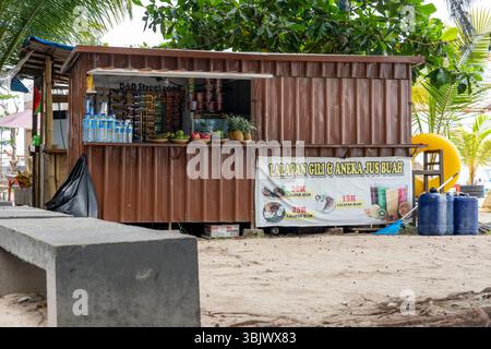 Gili, Lombok, Indonesia - 3 gennaio 2025: Piccolo stand alimentare con un cartello con scritto "Lalapan". Sul piedistallo sono presenti diverse bottiglie e una ciotola Foto Stock