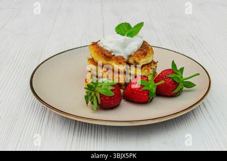 Una deliziosa pila di sciroppi fatti in casa, i tradizionali pancake al formaggio dell'Europa orientale. Le frittelle dorate sono ricoperte da un cucchiaio di sou Foto Stock