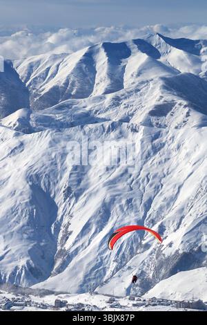 Vola a tutta velocità sulle montagne innevate sopra la stazione sciistica nelle soleggiate giornate invernali Foto Stock