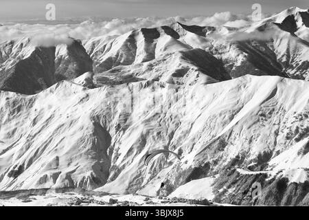 Vola a tutta velocità sulle montagne innevate sopra la stazione sciistica nelle soleggiate giornate invernali Foto Stock