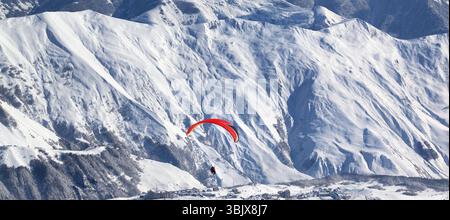 Vista panoramica sul parapendio sulle montagne innevate sulla stazione sciistica durante le soleggiate giornate invernali Foto Stock
