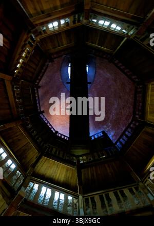 Vista verso l'alto di una scala a chiocciola all'interno di una torre in mattoni. La scala è realizzata in legno e ha un aspetto scuro e ombroso. La torre di mattoni. Foto Stock