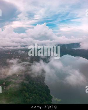 La foto aerea rivela la bellezza serena di Bali con nuvole che galleggiano sulle calme acque del lago Tamblingan. Foto Stock