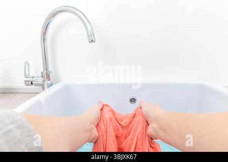 Mani femminili che lavano vestiti colorati nel lavandino Foto Stock