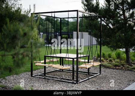 Tavolo circondato da sedie a dondolo collocate all'aperto in un tranquillo giardino Foto Stock