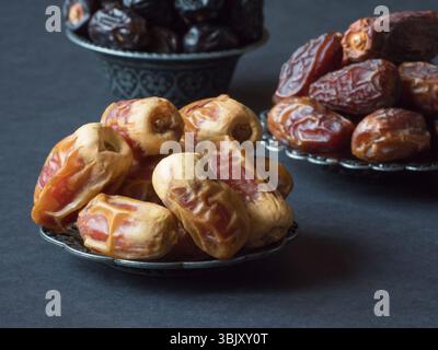 I frutti di datteri arabi sono disposti su una tavola scura. Primo piano. Foto Stock