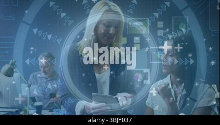 Donna bionda bionda con un tablet e presentazione dei dati in un ufficio open space, con un notebook Foto Stock