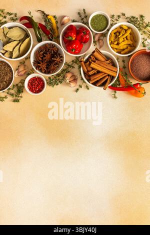 Una variopinta gamma di spezie secche ed erbe fresche disposte su un morbido sfondo beige, ideale per condire e aggiungere un ricco sapore ai piatti, vista dall'alto e spazio per le copie Foto Stock