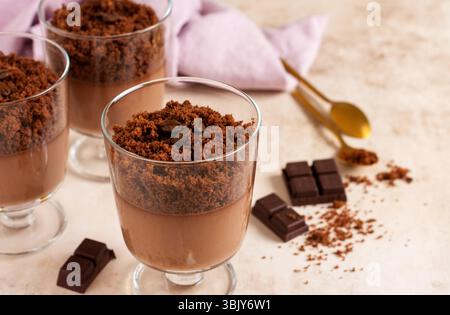 Mousse al cioccolato con brownie in vasetti di vetro su sfondo di ardesia, pietra o cemento. Delizioso dessert. Messa a fuoco selettiva Foto Stock