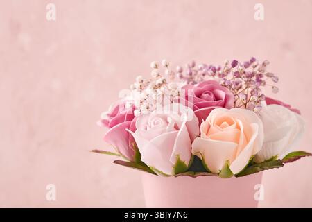 Composizione natalizia con bellissimi fiori di rose delicate in scatola rotonda rosa su sfondo rosa chiaro. Disposizione piatta, spazio di copia. Gree Foto Stock