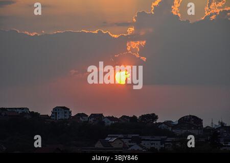 Panorama urbano al tramonto con sole dorato e cielo serale colorato Foto Stock