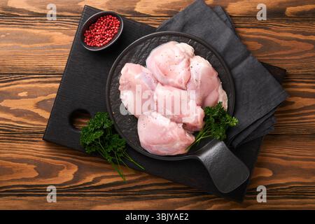 Filetto di coscia di pollo crudo senza pelle con erbe e spezie su vecchio fondo di legno. Carni di pollame da allevamento. Vista superiore con copia spac Foto Stock