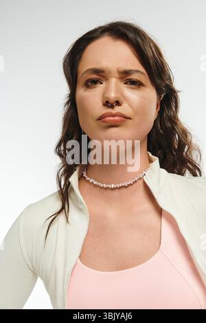 Una giovane donna elegante trasuda fiducia con un outfit alla moda ed un'espressione accattivante Foto Stock