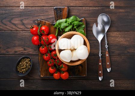 Insalata caprese, ingredienti per cucinare. Taglio di pannelli di legno con preparazione tradizionale caprese ingridienti: Mozzarella, toma Foto Stock