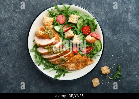 Insalata fresca con filetto di pollo alla griglia, lattuga, rucola, spinaci, pomodori, cetriolo e pesto, semi di sesamo con olive Foto Stock