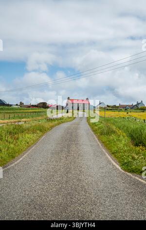 Vista generale di Sandwick e Hoswick, Shetland, che mostra strade tortuose, case sparse e paesaggio costiero ondulato sotto cieli luminosi. Foto Stock