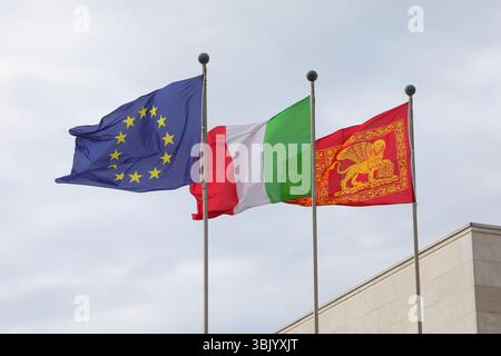 Venezia, VE, Italia - 6 maggio 2025: Tre grandi Bandiere dell'Unione europea Blu con stelle gialle e tricolore d'ITALIA e bandiera del Veneto con gol Foto Stock