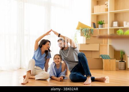 La risata riempie l'accogliente salotto mentre una famiglia si diverte a divertirsi, creando un legame gioioso mentre è circondata da una calda luce naturale. Foto Stock
