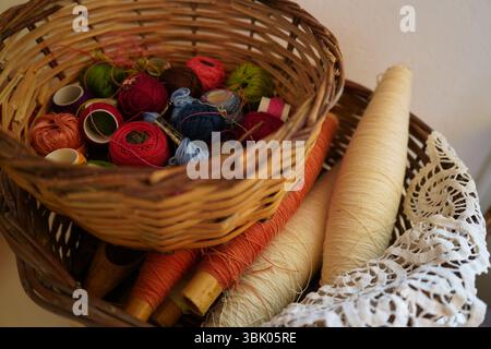 Creta, Grecia, 14 giugno 2025: I cesti intrecciati contengono bobine, palline e coni di filo vibranti in vari colori, tra cui rosso, verde e rosa. Foto Stock