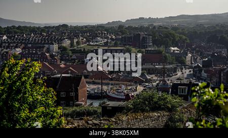 WHITBY, Regno Unito - 12 GIUGNO 2025 - Vista panoramica del porto di Whitby nel North Yorkshire, Inghilterra, con barche, edifici tradizionali e il panoramico nord Foto Stock