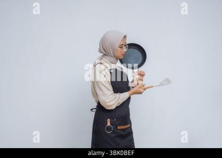 Giovane musulmano asiatico che indossa hijab e grembiule nero Foto Stock