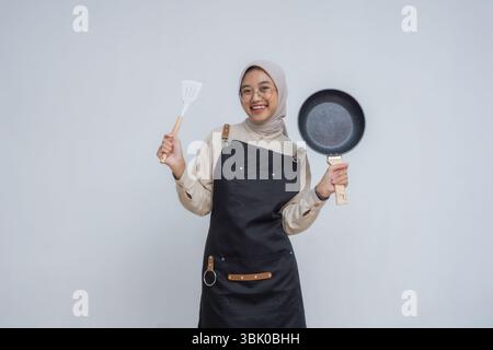Giovane musulmano asiatico che indossa hijab e grembiule nero Foto Stock