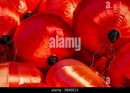 Lanterne di seta rosso brillante con dettagli neri e fili disposti in un gruppo festivo per festeggiare o decorare. Foto Stock